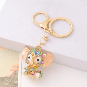 Golden elephant keychain with colorful rhinestones on a white geometric platform