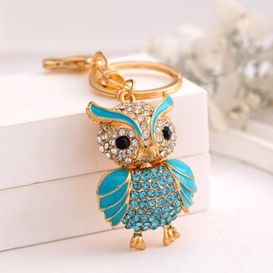 Detail of owl keychain with blue crystals and sparkling rhinestones on golden metal