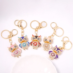 Five colorful owl keychains with crystals and enamel on a decorative white plate