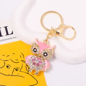 Close-up of pink enamel owl keychain with sparkling crystals and golden metal lobster clasp
