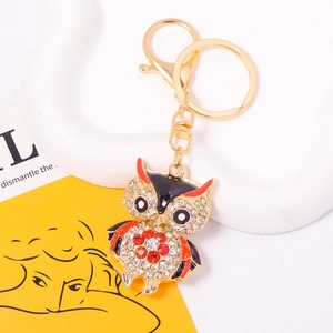 Close-up of golden owl keychain with sparkling red and white rhinestones on magazine