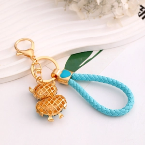 Creative gold owl keychain with sky blue braided rope and heart charm on white background