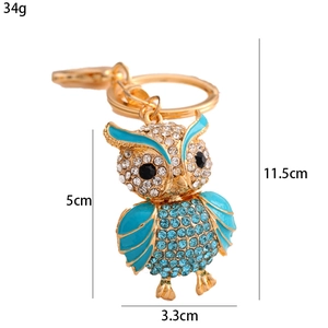 Golden owl keychain with blue enamel wings and sparkling rhinestones measuring five centimeters