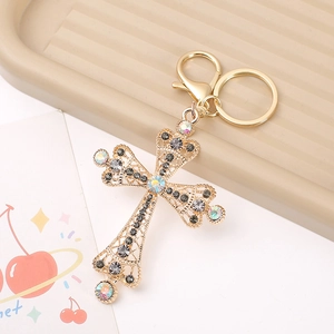 Macro shot of a golden hollow cross keychain with iridescent gems and grey rhinestones