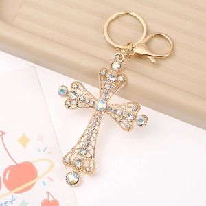 Luxurious cross keychain with gold filigree, colorful crystals and pearls on a tray