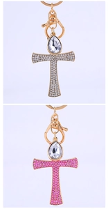 Close-up of golden cross keychain with sparkling pink and white rhinestones and large crystal