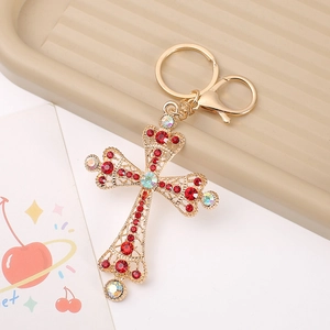 Close-up of golden hollow cross keychain with red rhinestones and lobster clasp detail