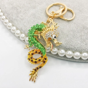 Close-up of golden dragon keychain with green enamel and sparkling rhinestones