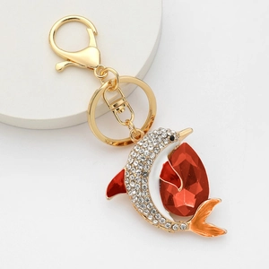 Golden dolphin keychain with white rhinestones and a large red teardrop gemstone