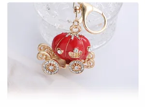 Vue détaillée du porte-clés carrosse citrouille doré avec émail rouge et strass brillants