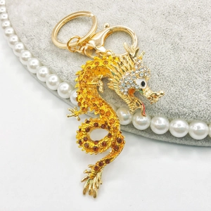 Close-up of golden dragon keychain with amber rhinestones and lobster clasp on velvet
