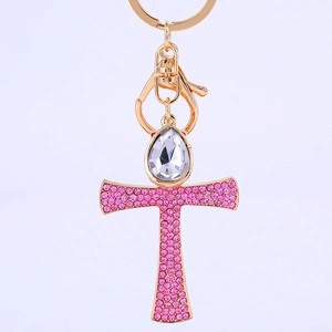 Golden metal cross keychain with pink rhinestones and a pear-shaped crystal pendant
