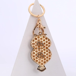 Porte-clés chouette dorée avec motif fleurs ajouré et strass sur présentoir blanc