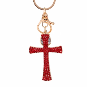 Golden cross keychain with red rhinestones on white background for car or bag decoration