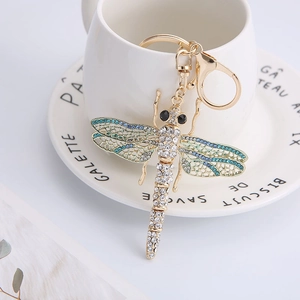 Detailed close-up of a golden dragonfly keychain with blue rhinestones on a white mug