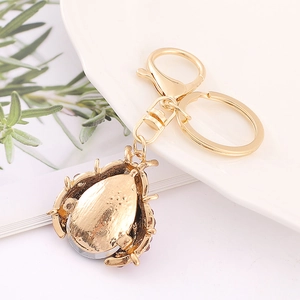 Golden ladybug keychain with purple rhinestones on a white ceramic plate