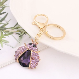 Detail of ladybug keychain with purple crystals and gold alloy beetle bag charm decoration