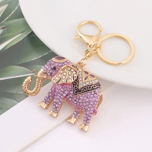 Detailed view of elephant keychain with purple rhinestones on a white ceramic plate
