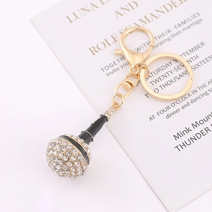 Sparkling microphone keychain with gold metal base and white rhinestones on invitation card