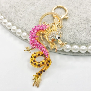 Llavero de dragón chino dorado con cristales rosas y rojos en expositor de joyería