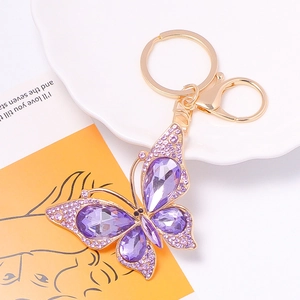 Detail view of purple crystal butterfly keychain with gold lobster clasp on decorative tray