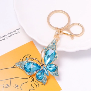 Close-up of golden butterfly keychain with blue rhinestones and waterdrop gems