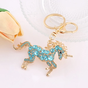 Porte-clés licorne dorée orné de strass bleu clair sur fond blanc avec tulipes