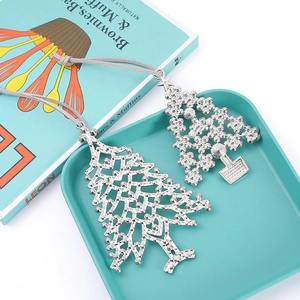 Close-up of two silver Christmas tree pendants with rhinestones on a teal tray