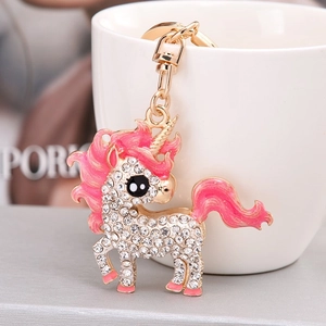 Sparkling enamel unicorn keychain with gold plating and rhinestones on a white cup