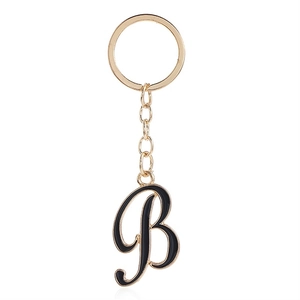 Detail of cursive letter B keychain with black enamel finish and golden metal ring