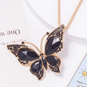 Close-up of golden butterfly pendant with black faceted stones and fine diamond inlay