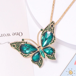 Macro shot of large golden butterfly pendant with deep green crystals and rhinestones