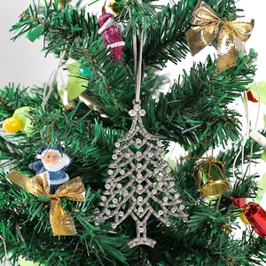 Detailed view of silver metal Christmas tree pendant with rhinestones on a festive tree branch