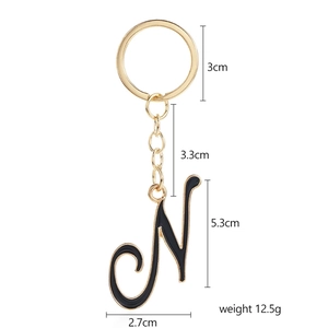 Golden metal keychain with cursive letter N in black enamel for bags and accessories