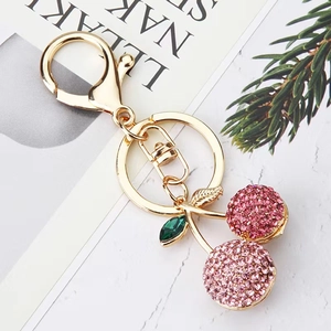 Detail of pink rhinestone cherry keychain with gold alloy finish and green leaf gemstone