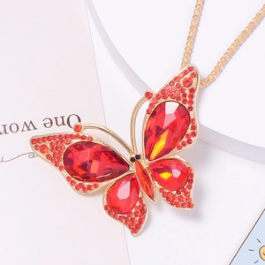Detail of red rhinestone butterfly pendant with golden alloy frame and intricate crystals