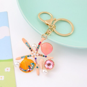 Détail du porte-clés étoile de mer avec strass colorés, coquillage rose et perles