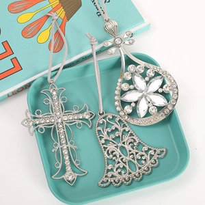 Detalle de adornos navideños plateados con pedrería en forma de cruz, campana y flor