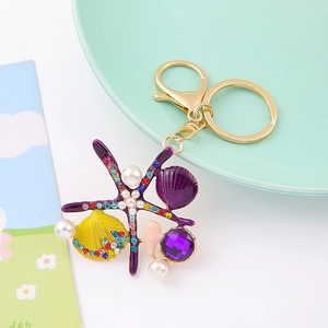 Détail du porte-clés étoile de mer avec émail violet, strass colorés et perles chic
