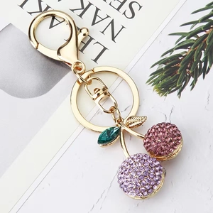 Detail of cherry keychain with pink and purple rhinestones on a gold alloy metal base