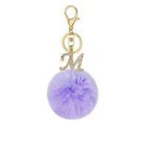 Detail of purple faux fur pompom keychain with golden lobster clasp and rhinestone letter M