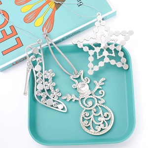 Detailed close-up of hollowed silver metal Christmas charms including snowman and star