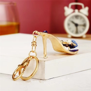 Elegant gold high heel keychain with blue floral details and rhinestones on a white stand
