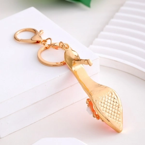 Detail view of a rose gold high heel keychain with floral accents on a geometric pedestal
