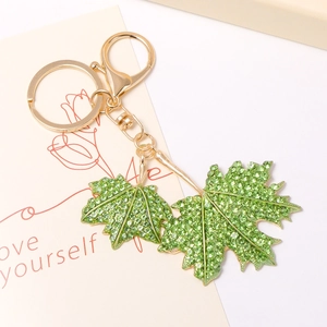 Vue macro d'un porte-clés feuille d'érable avec strass verts et finitions dorées