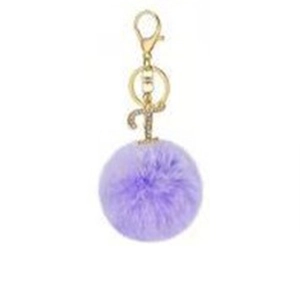 Detail view of purple plush ball keychain with a gold letter T pendant and crystals