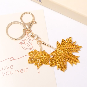 Détail macro du porte-clés feuille d'érable doré avec strass ambrés et fermoir en D
