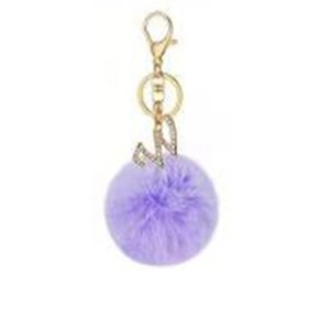 Detail of purple faux fur pompom keychain with golden rhinestone letter W charm
