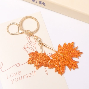 Détail d'un porte-clés feuille d'érable avec strass orange et finition plaquée or