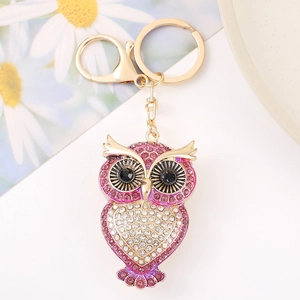 Detailopname van gouden uil sleutelhanger met roze strassteentjes en karabijnsluiting decor